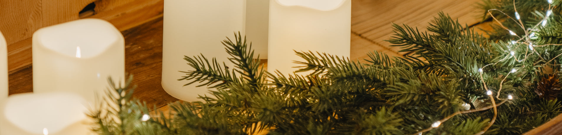 Árbol de Navidad con luces y velas blancas alrededor.